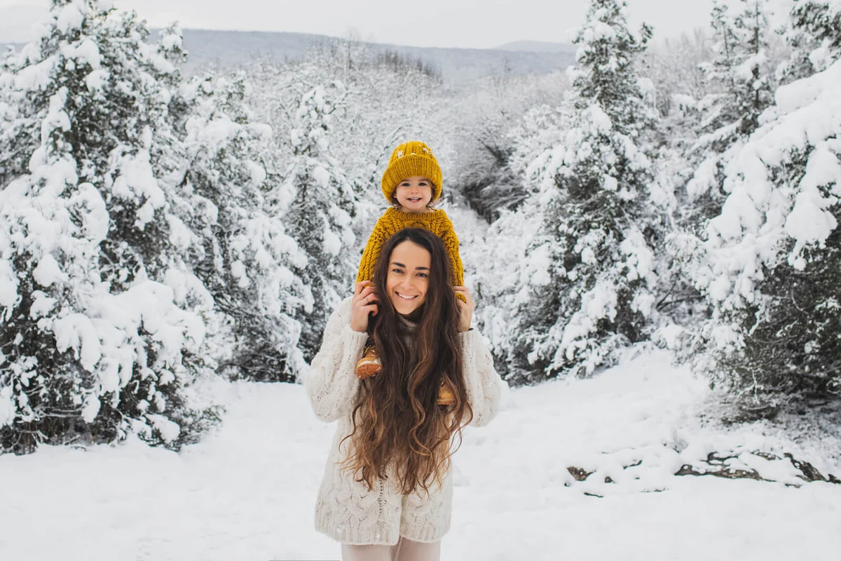 Happy family portrait of pretty young mom and baby girl sitting on neck