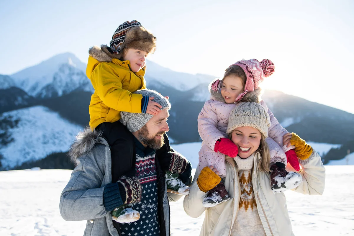 family with two small children enjoying snow in winter nature