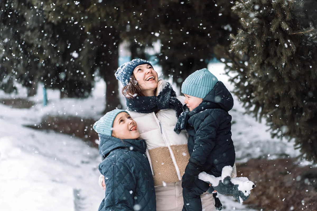 Mom with son and daughter catching snow with their hands
