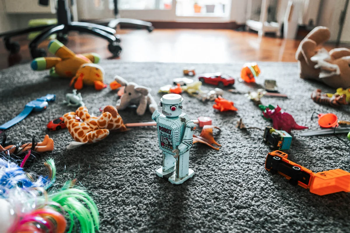 Toy robot surrounded by other toys on the carpet in child bedroom