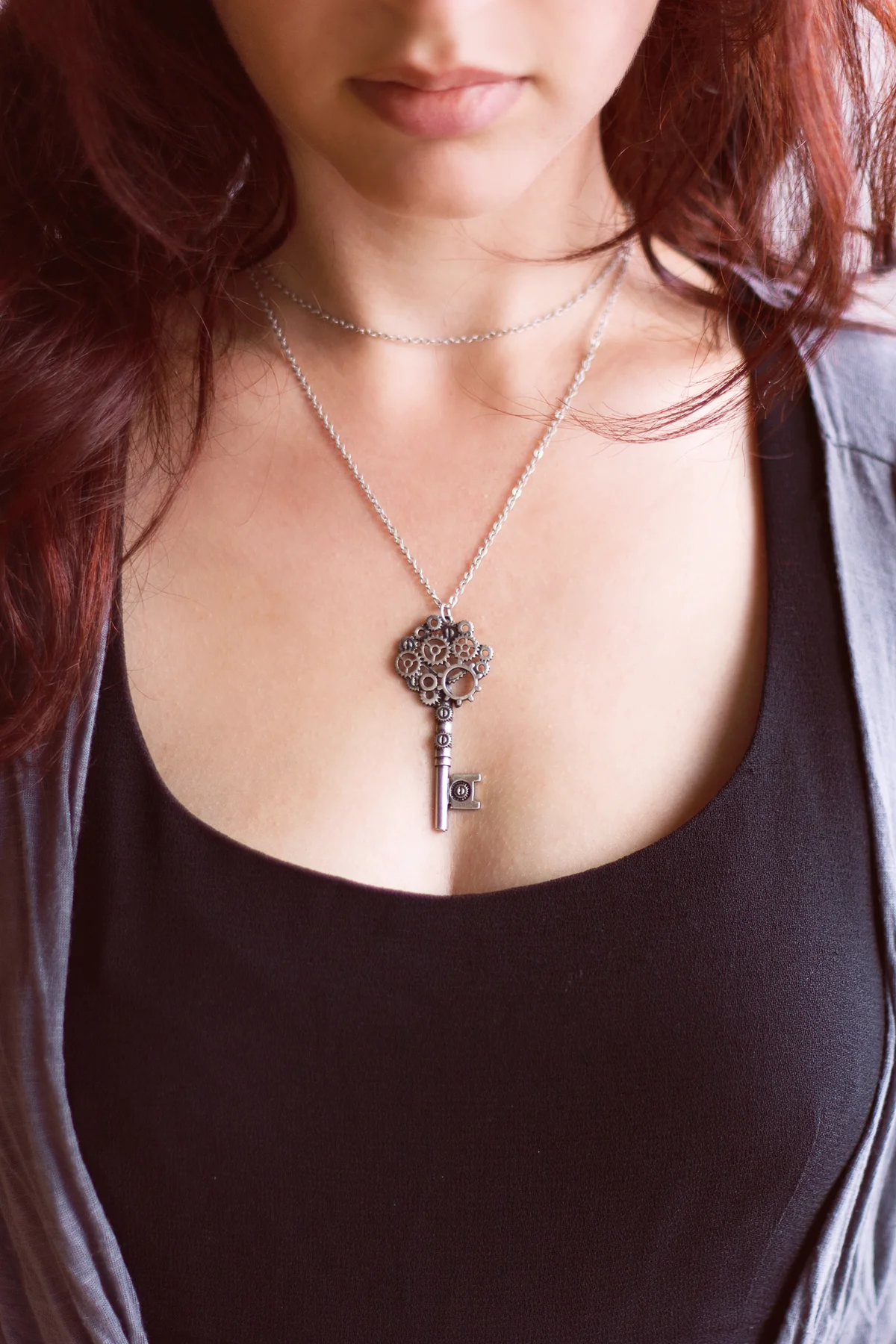 Woman with dark red hair wearing a vintage key necklace