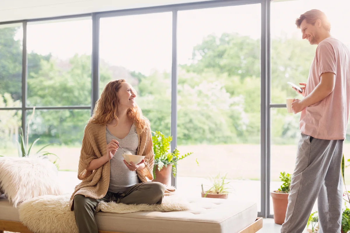 Pregnant couple eating breakfast in living room