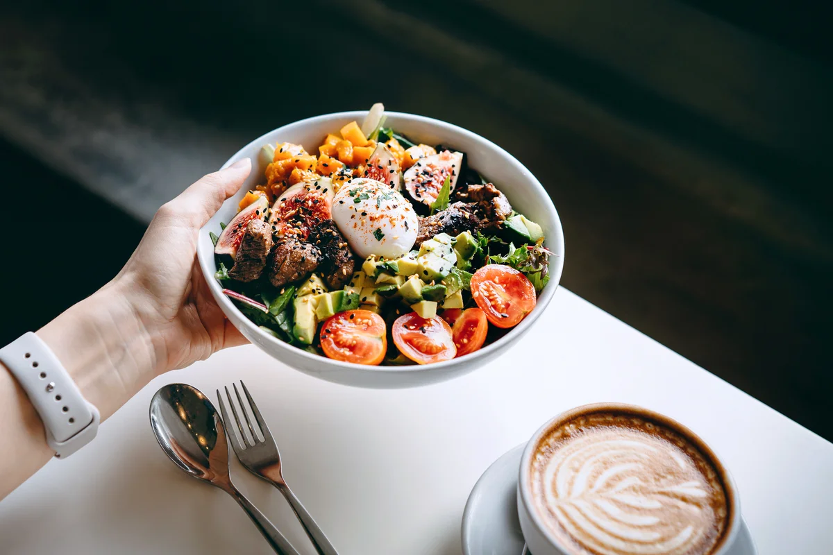 Woman holding a bowl of fresh beef Cobb salad