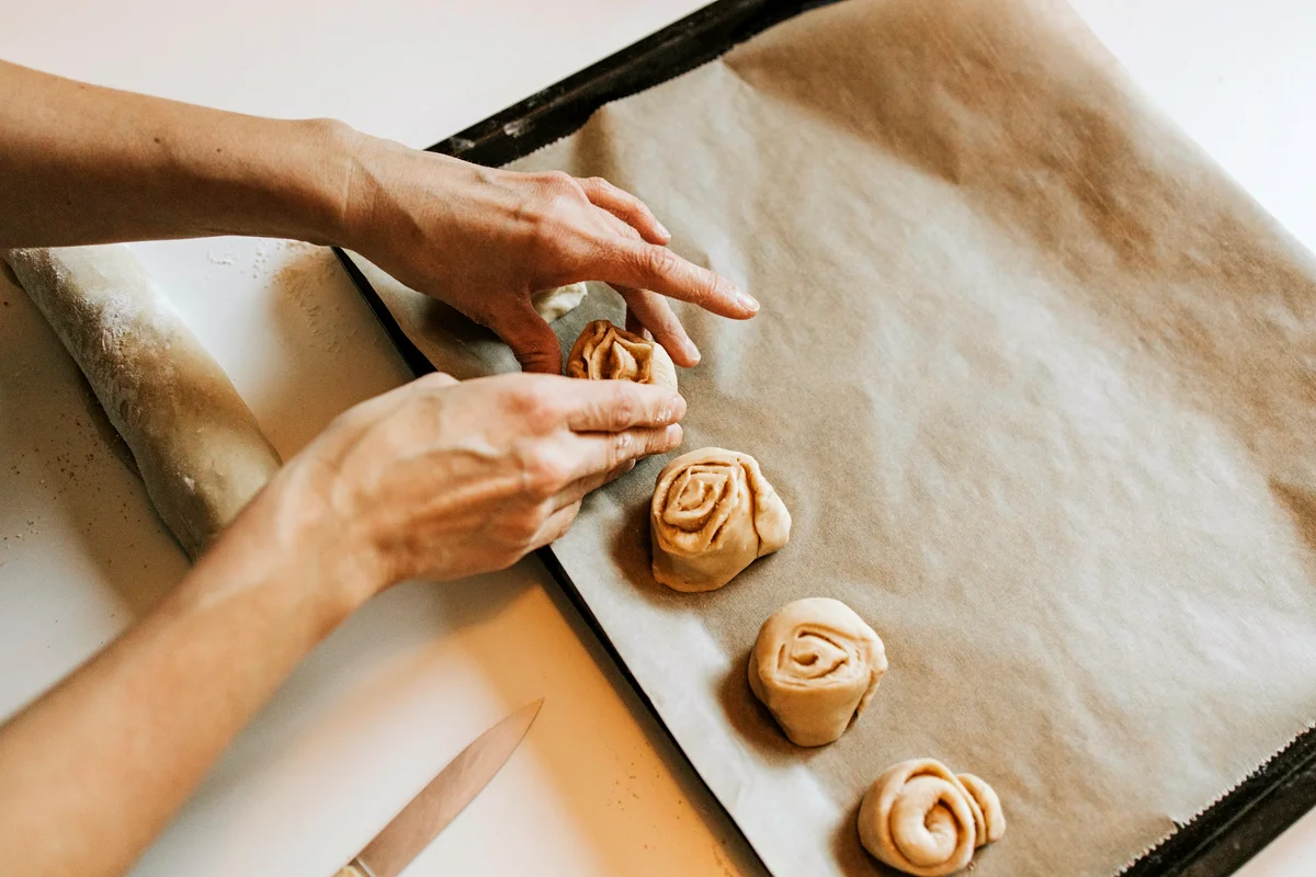 Woman arranging rolls on baking sheet