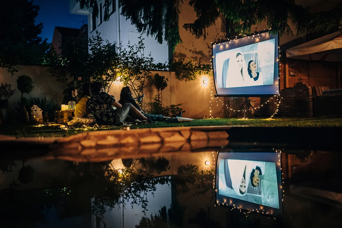 Friends watching movie on the video projector in the backyard garden