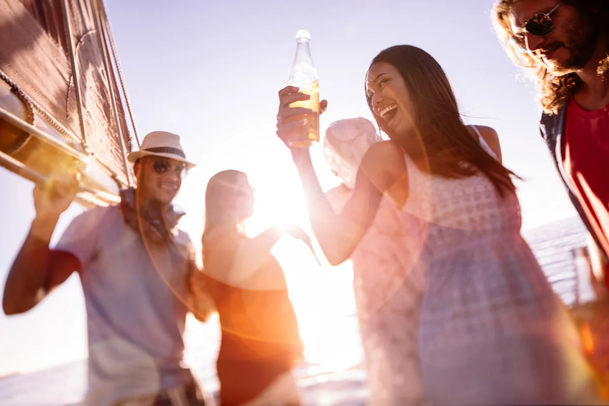 Friends laughing and dancing on a yacht at sunset
