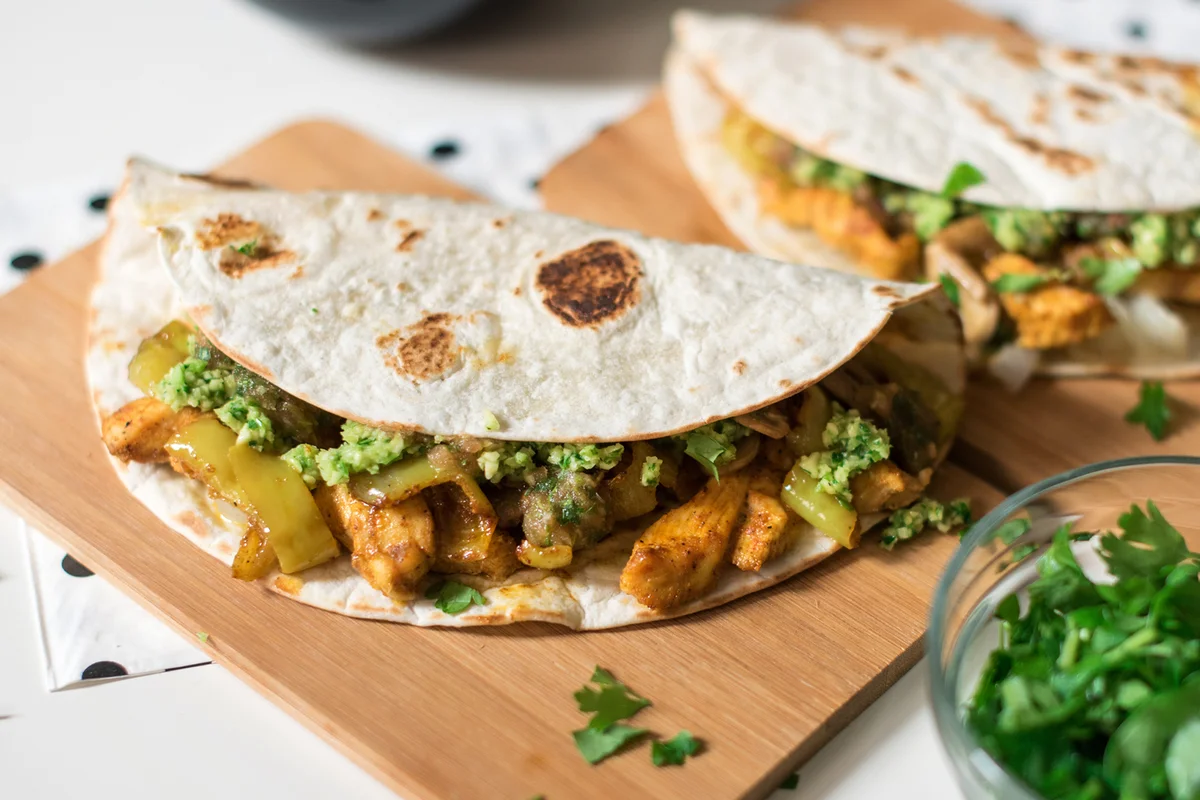 Homemade chicken tacos with peppers served on a wooden cutting board