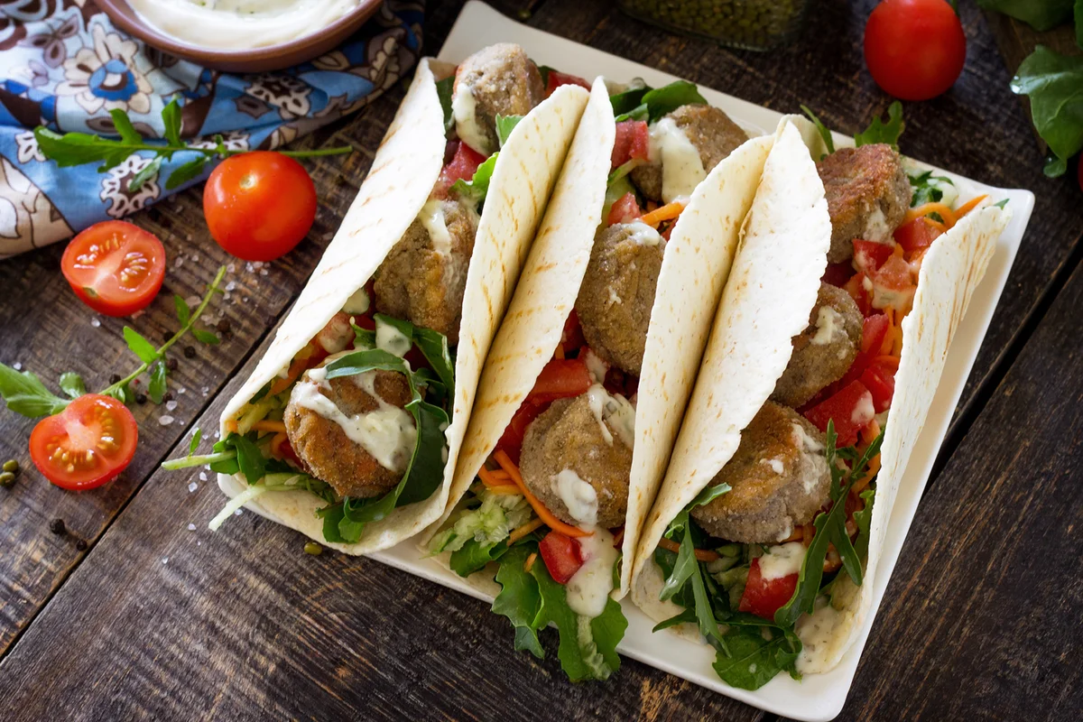 Delicious fresh homemade tortilla wrap with falafel and fresh salad on the table