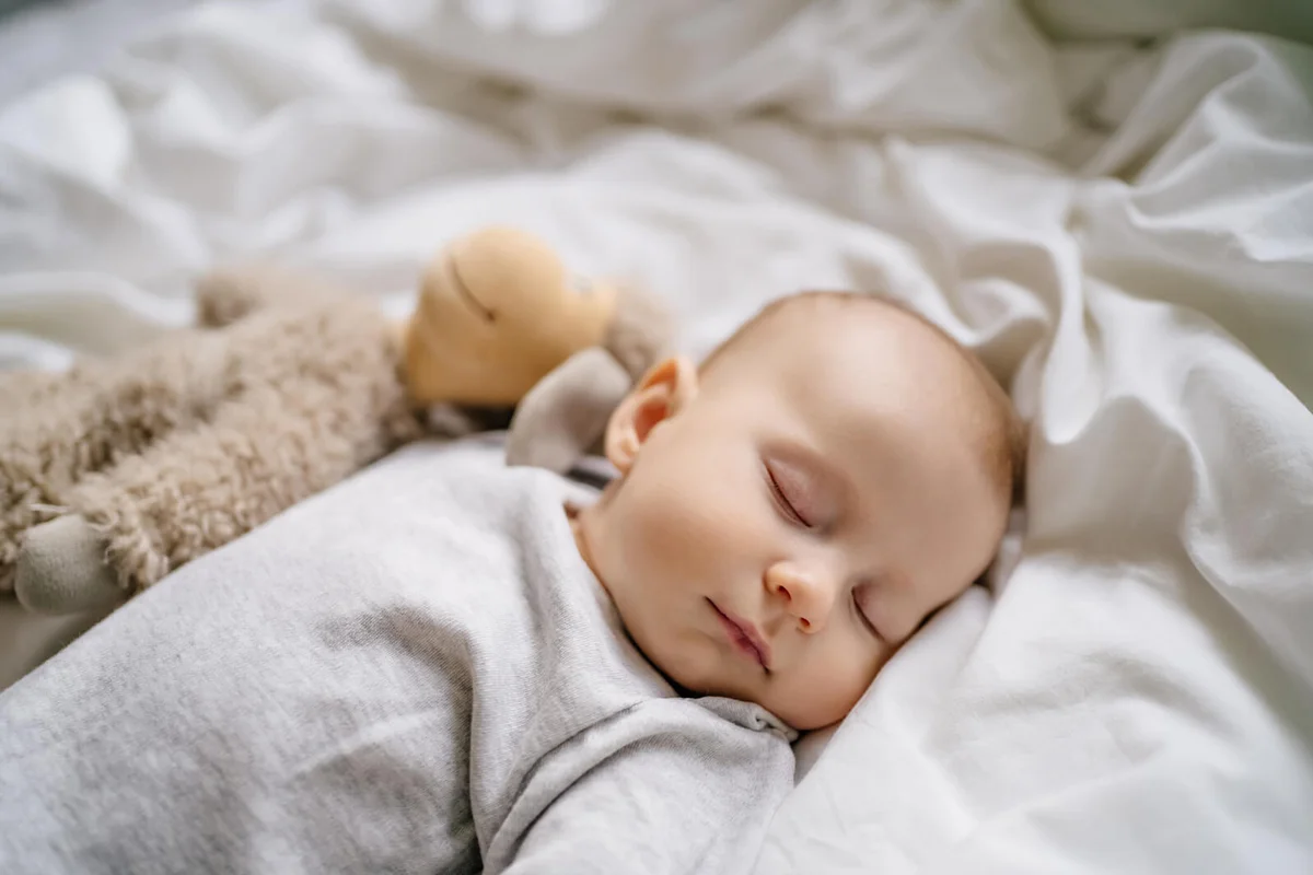 Little newborn baby lying down in cradle crib in bed