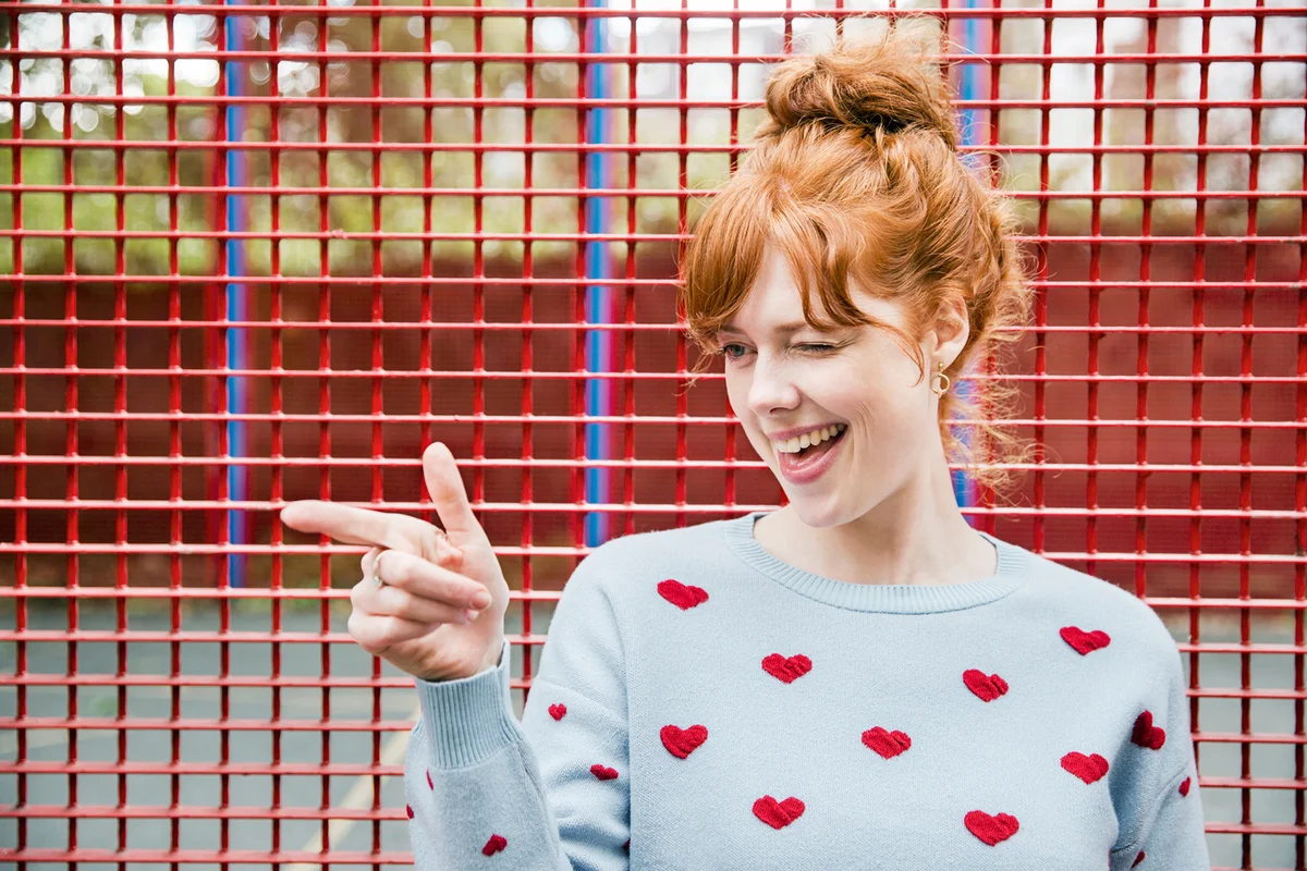 Young woman winking and pointing
