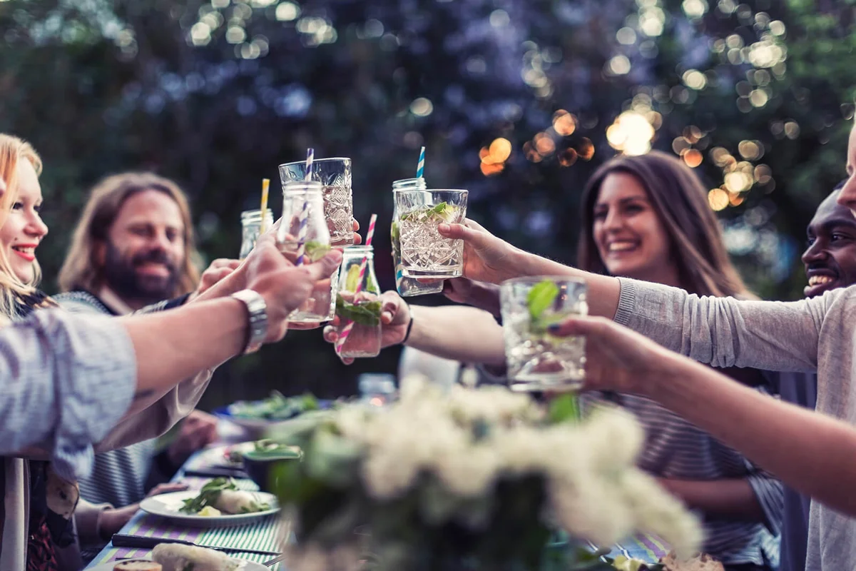friends toasting at dinner table in yard