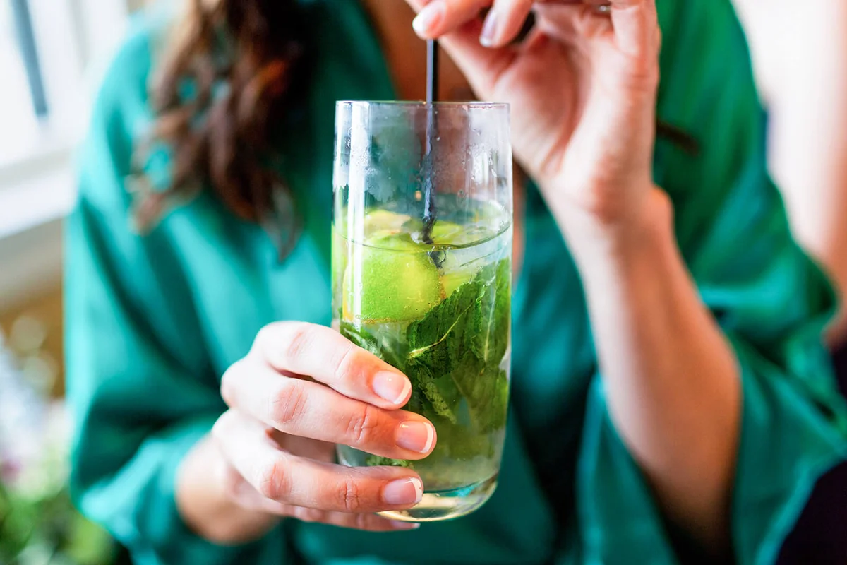 Woman holding and drinking a mojito with straw