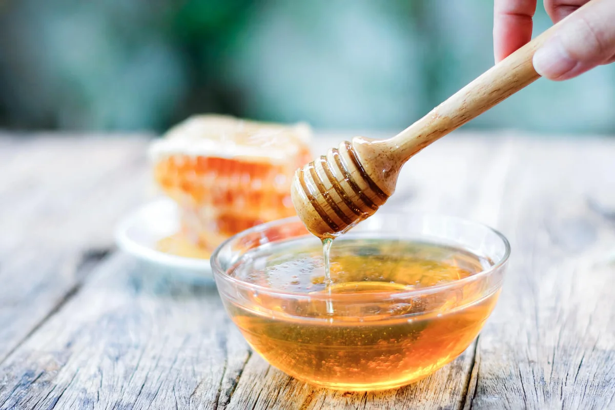 Honey dipper and honeycomb on table
