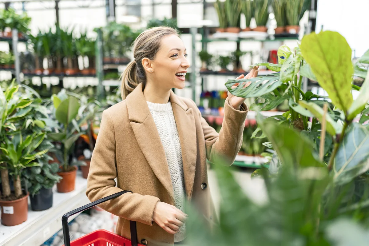 Young woman in garden center choosing plants