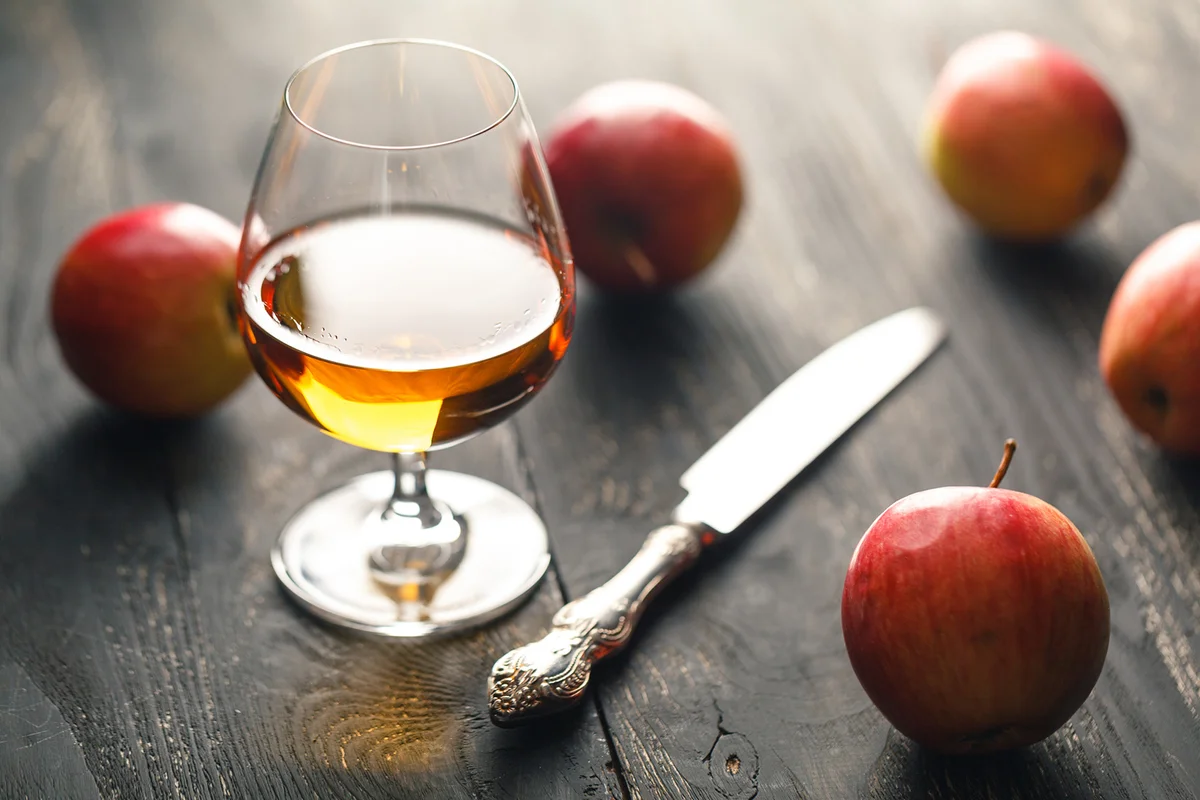 Whiskey and apples on dark wooden table
