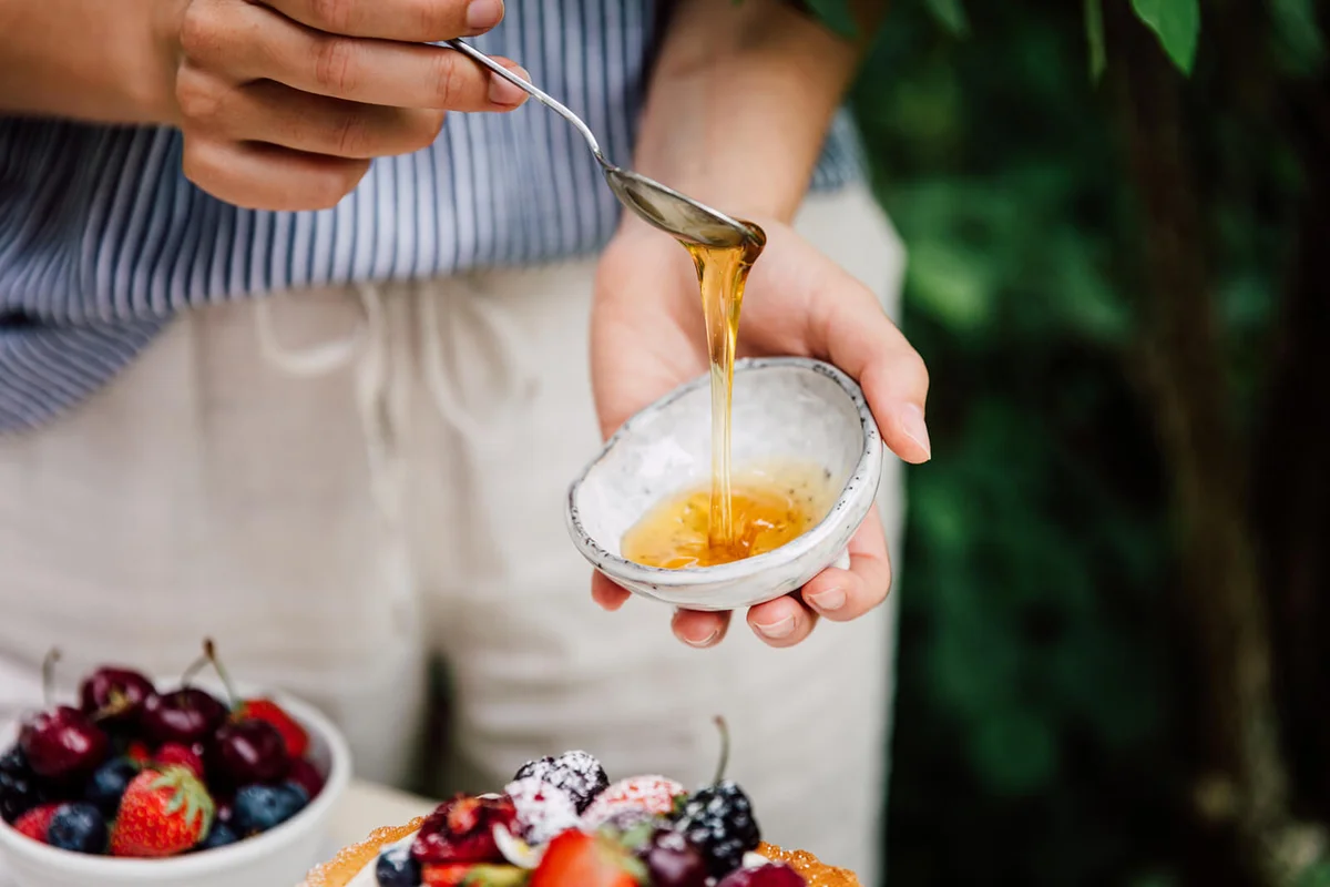 Woman adding honey on the cake