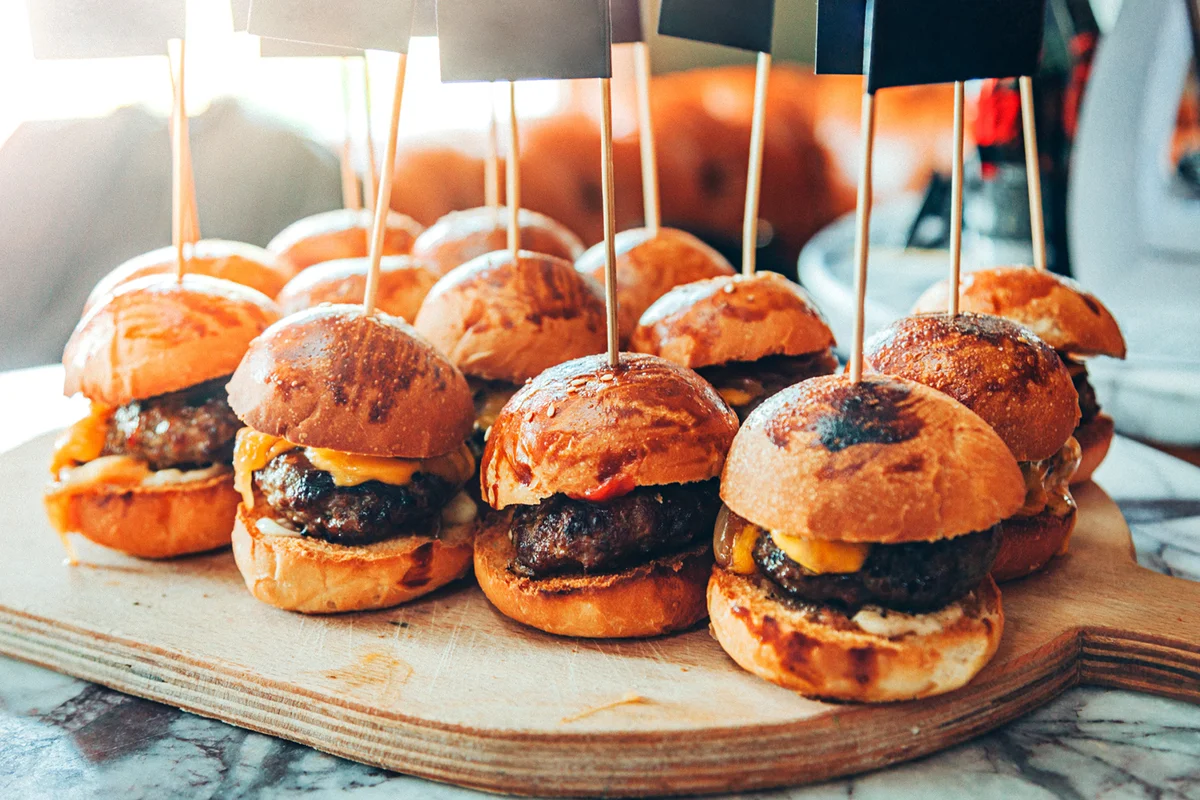 Assorted mini delicious cheeseburger sliders with cheese, onion and sauces