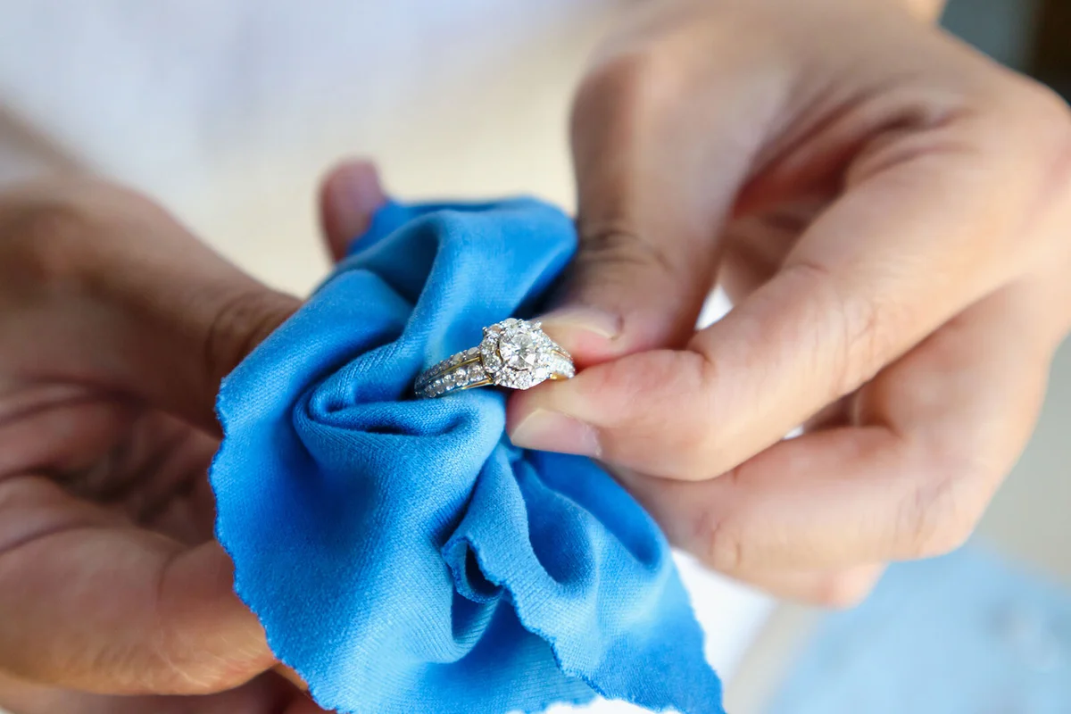 Jeweller hand polishing and cleaning jewelry diamond ring with micro fiber fabric