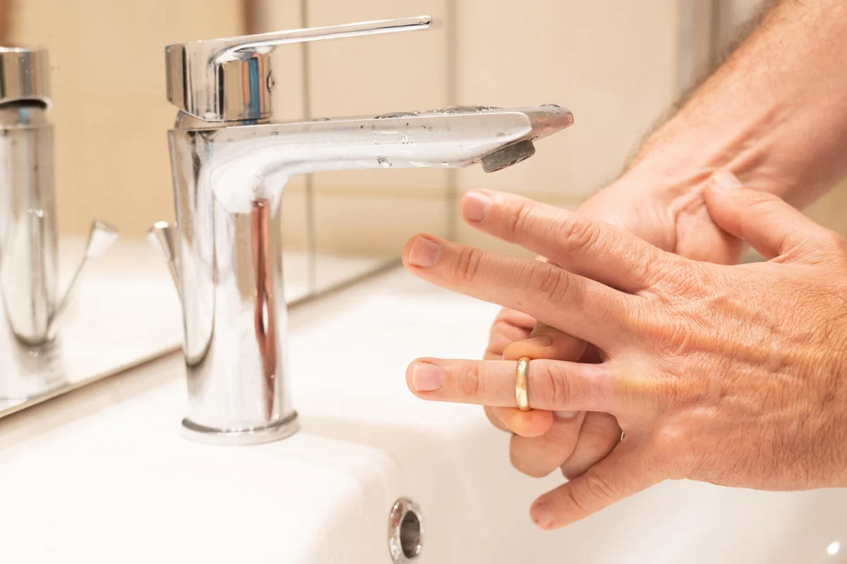 A man removes his wedding ring in a bathroom