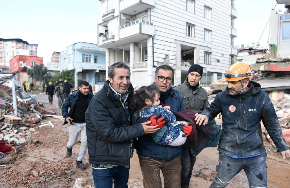 men rescue a child after earthquake