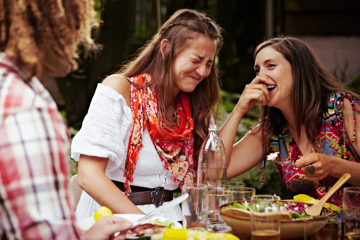 Two women laughing together at dining table