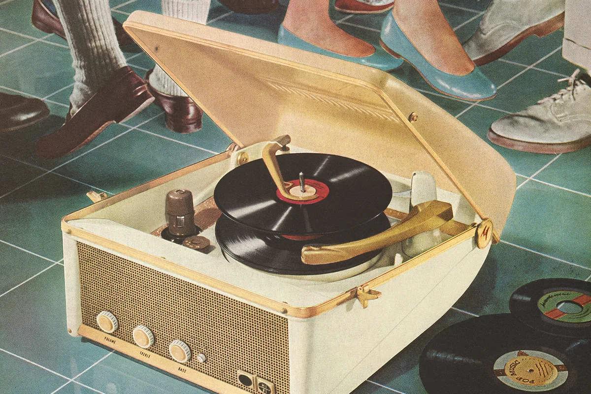 Vintage photograph of a portable record player on the floor in front of dancing feet