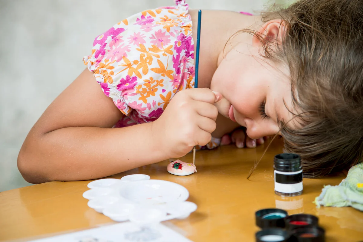 girl painting rock on desk