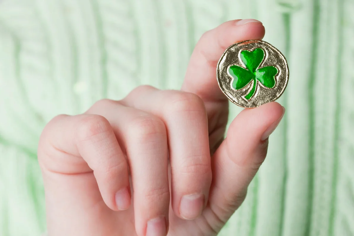 girl's hand holding a clover-shaped button