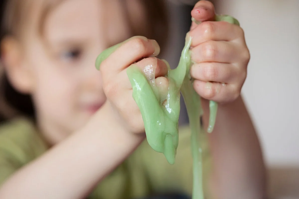 Child squeezing novelty green slime through fingers