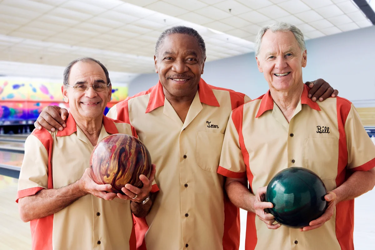 Men in team uniforms holding bowling balls