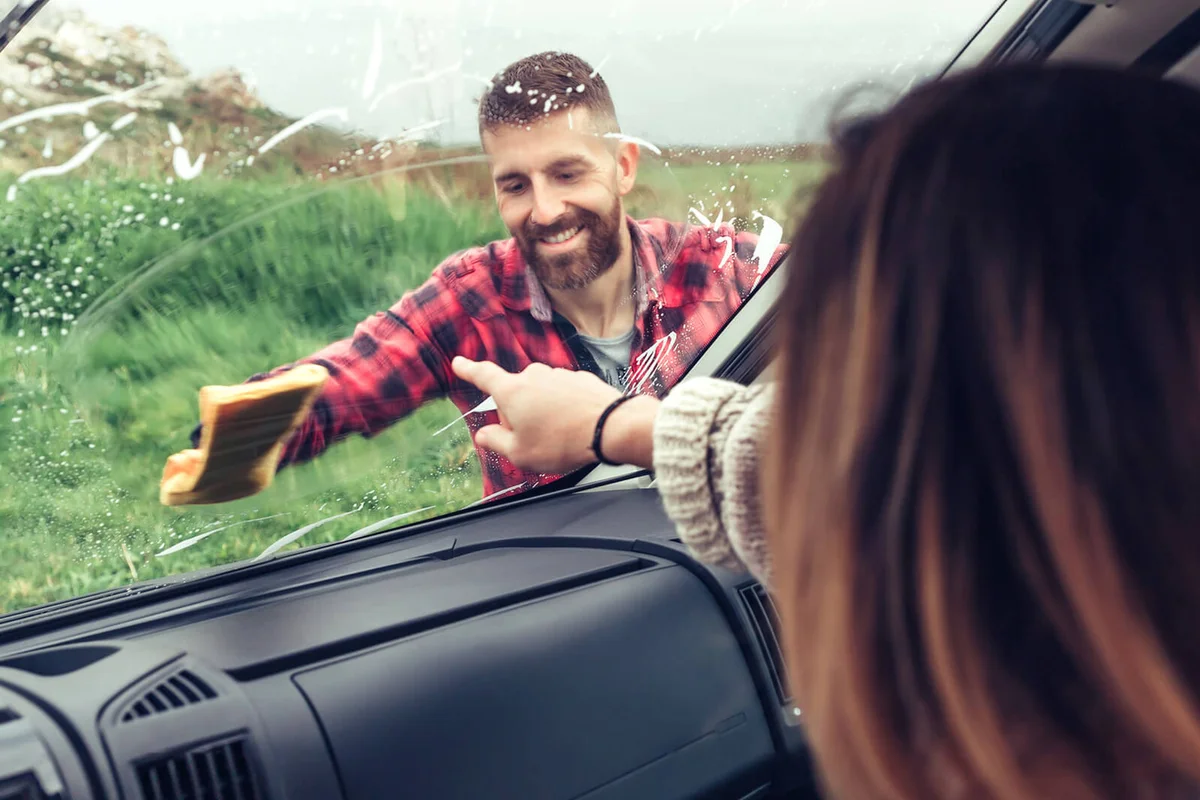 Man Cleaning Windshield Of Car
