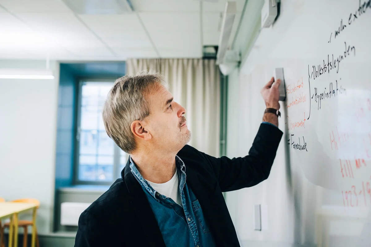 Male teacher erasing text on whiteboard