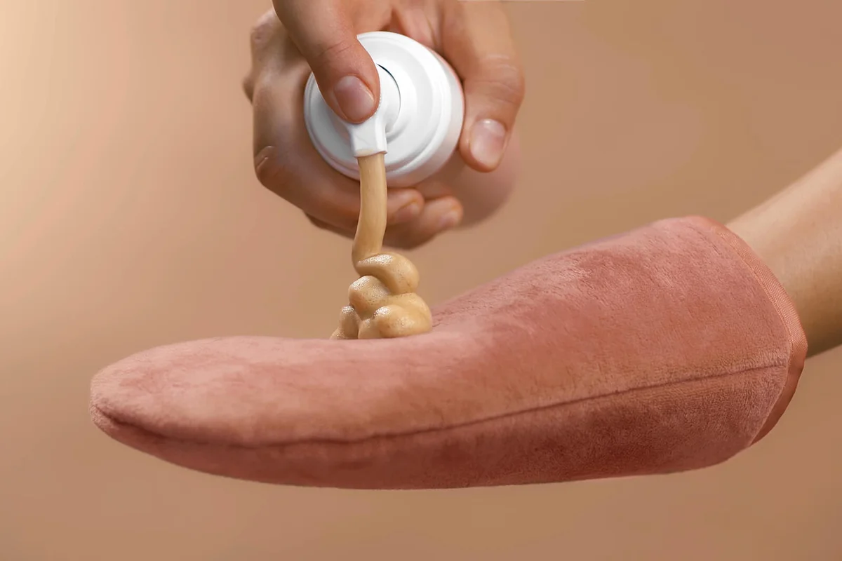 Applying self-tanner mousse to a rose massage glove