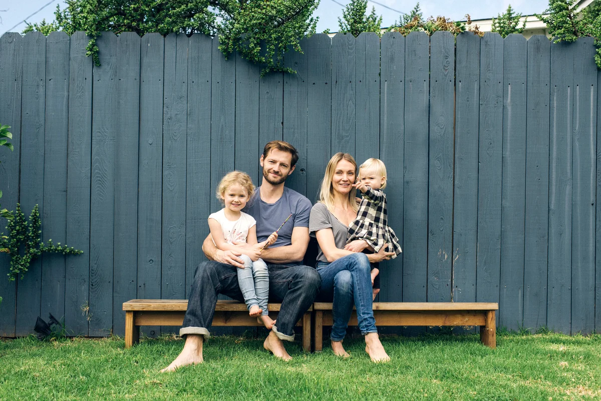 Happy parents and children sitting on seats against fence at yard