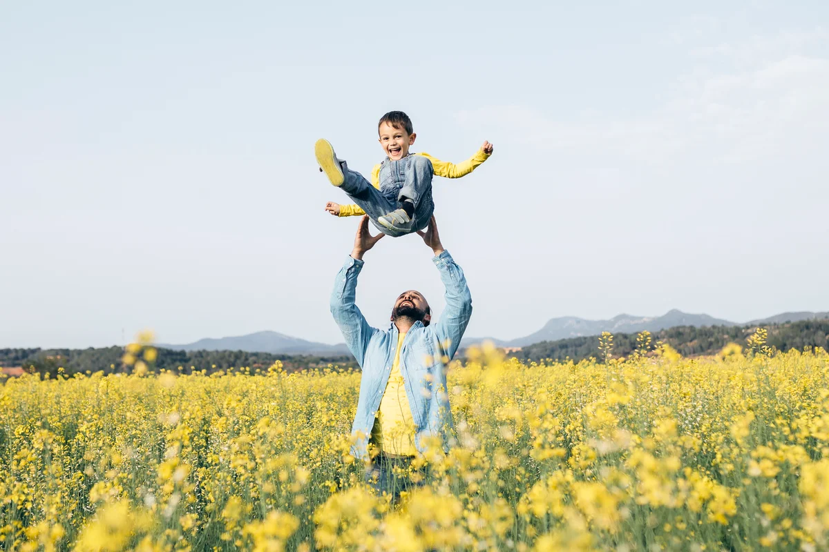Father and little son having fun together in a flower field