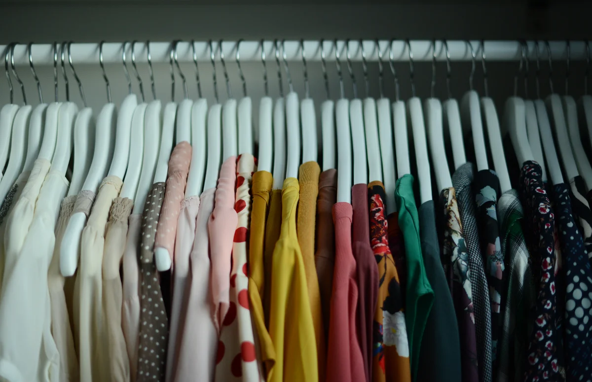Blouses hanging on coathangers in a row arranged by color