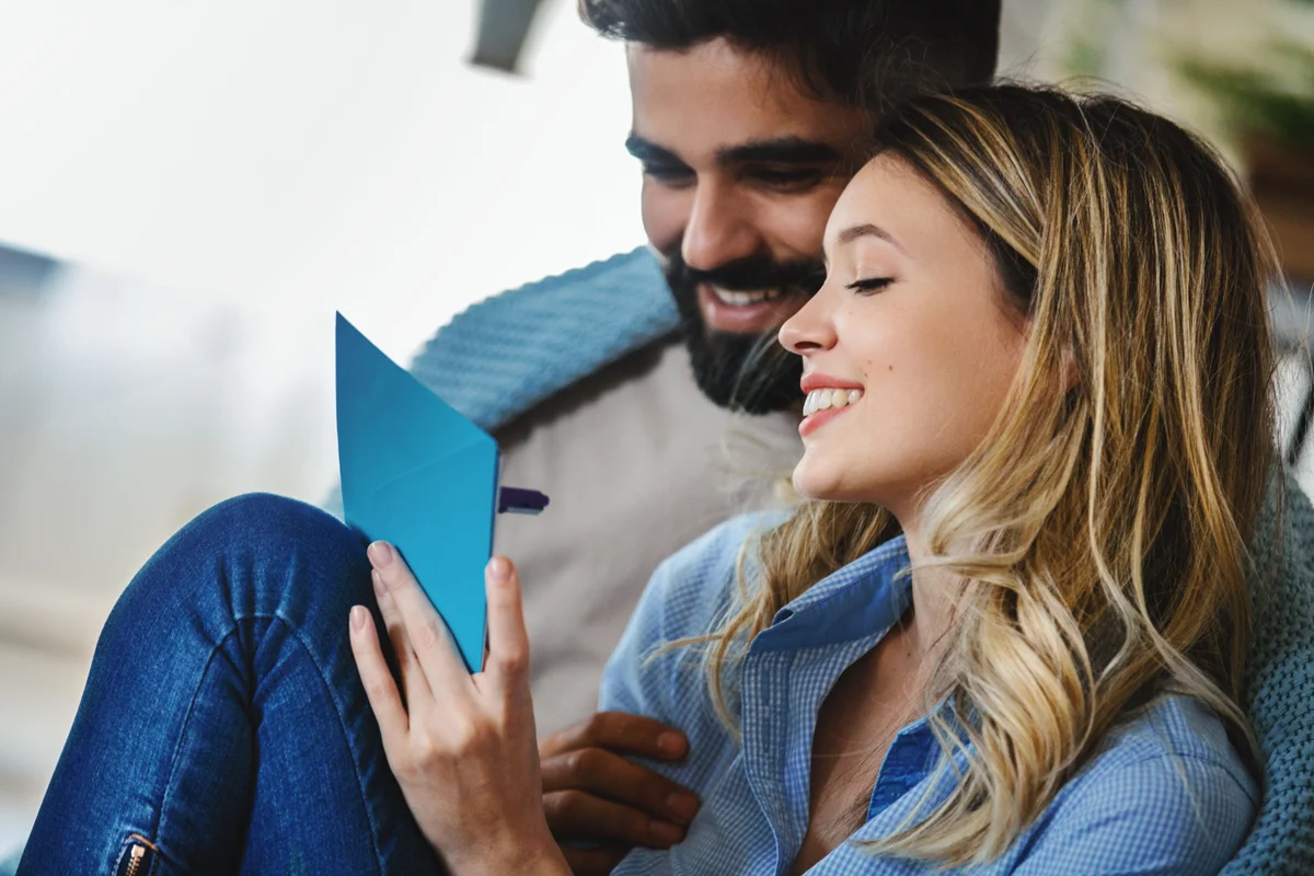 Young couple writing a wedding invitation together.