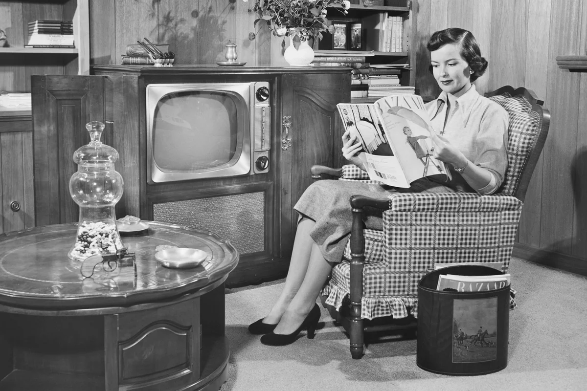 Woman sitting in armchair, reading magazine