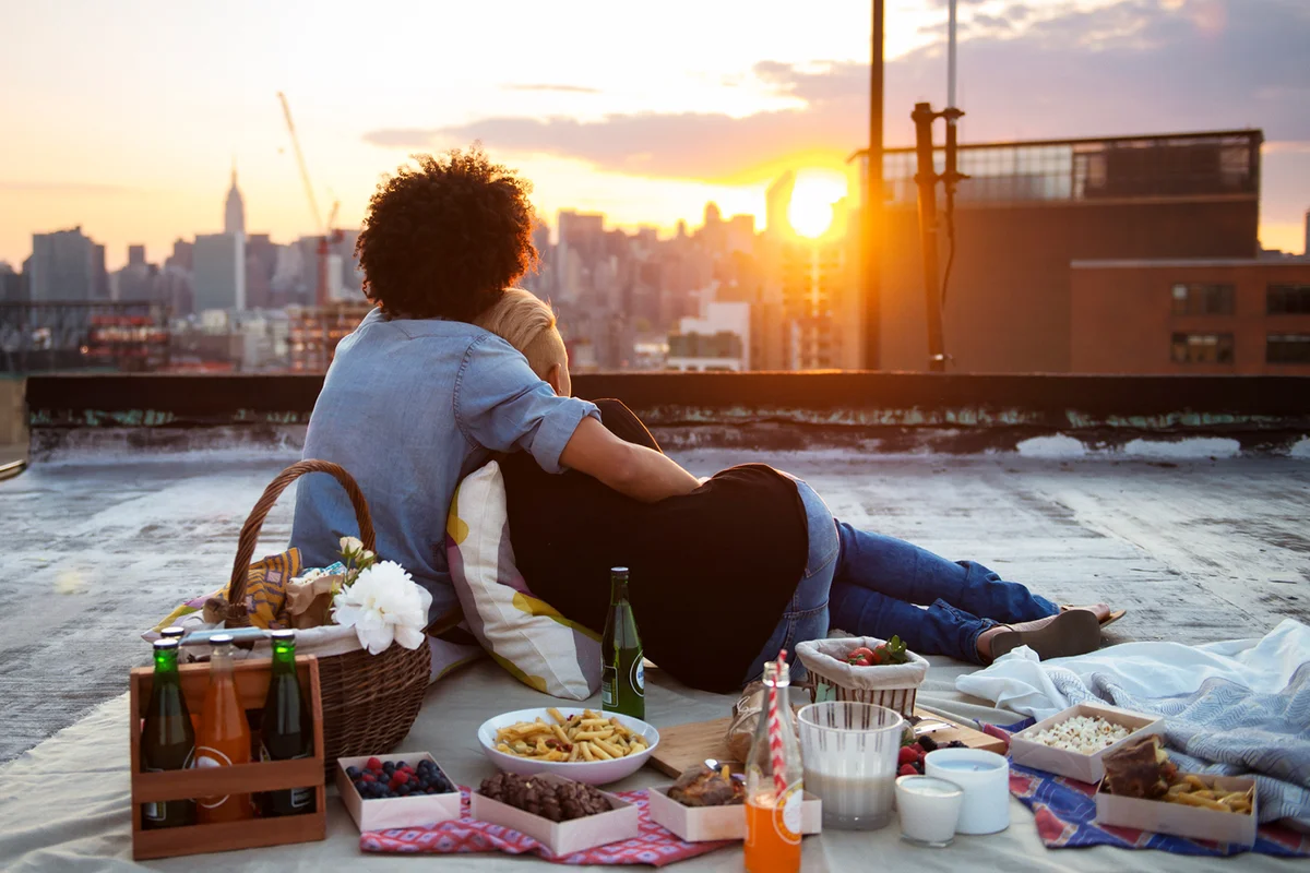 Couple relaxing on rooftop against sky during picnic