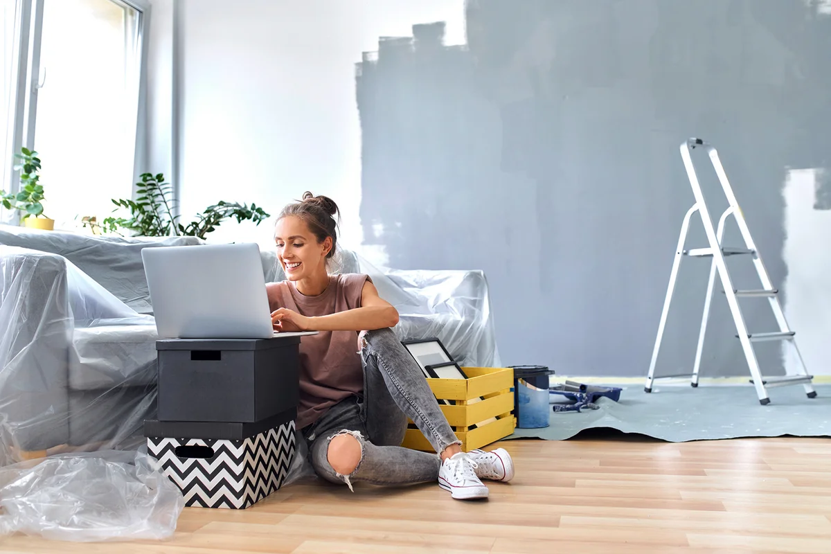 Smiling woman working on laptop while sitting by sofa at home