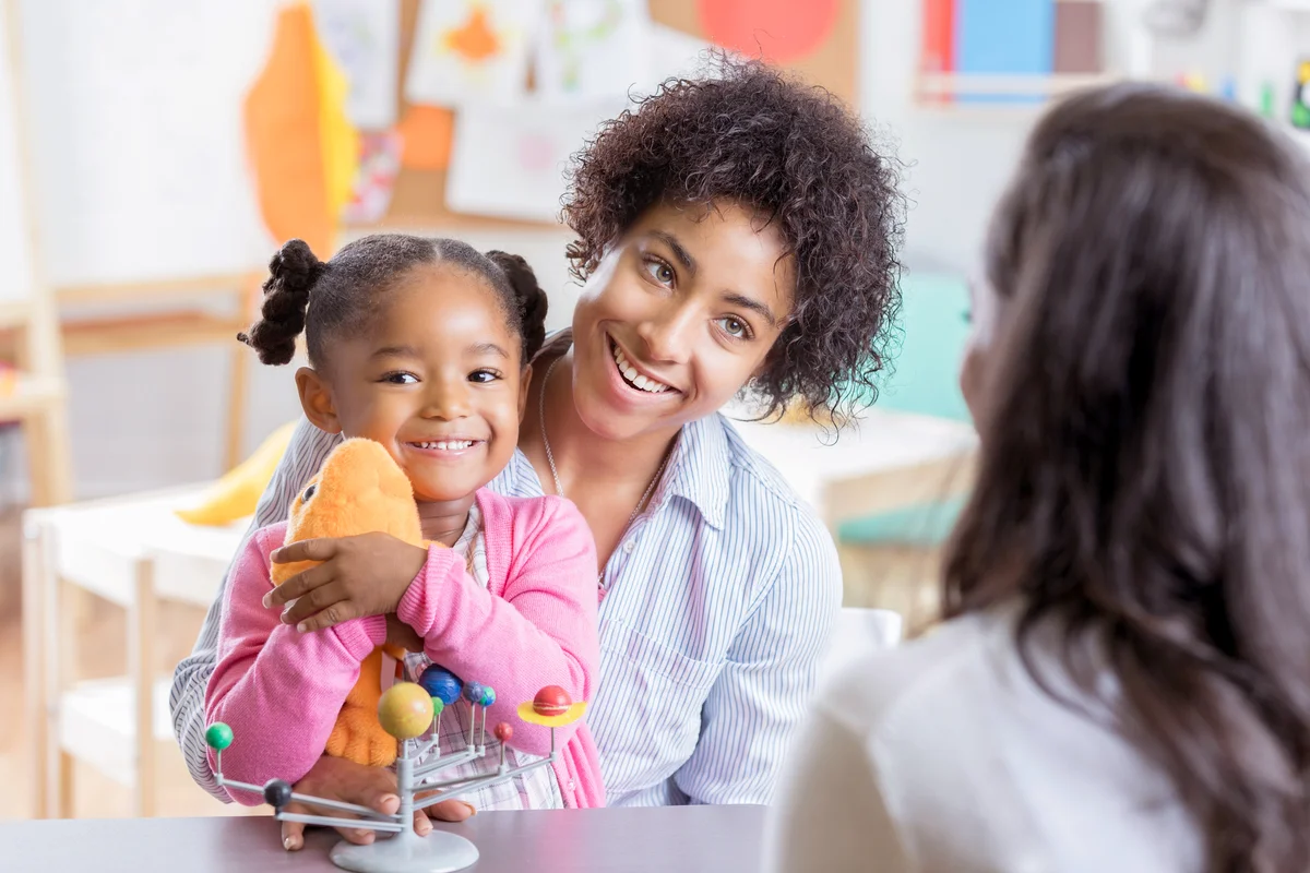 Preschool girl sits in her mother's lap in school interview