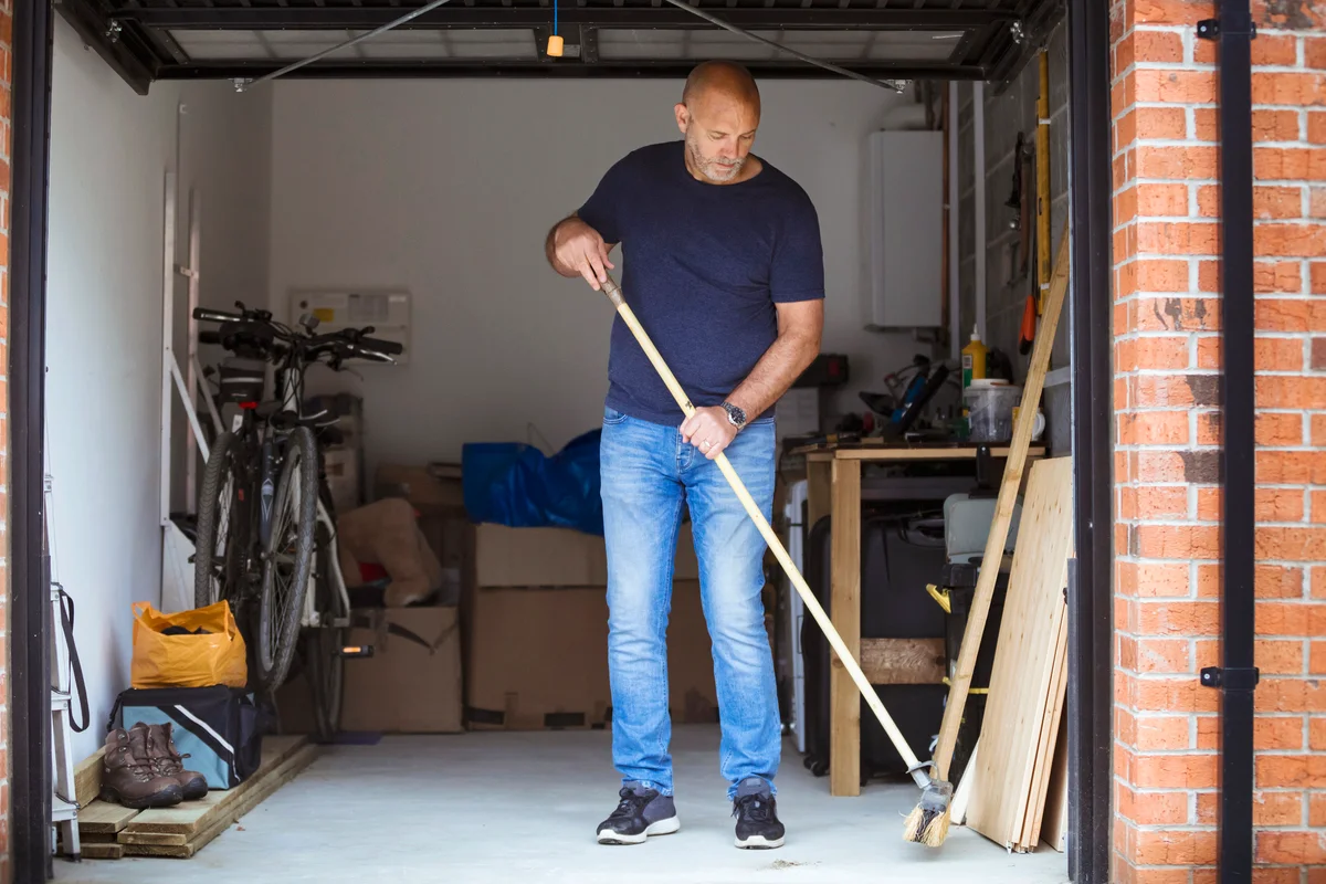 Man sweeping the floor of his home garage