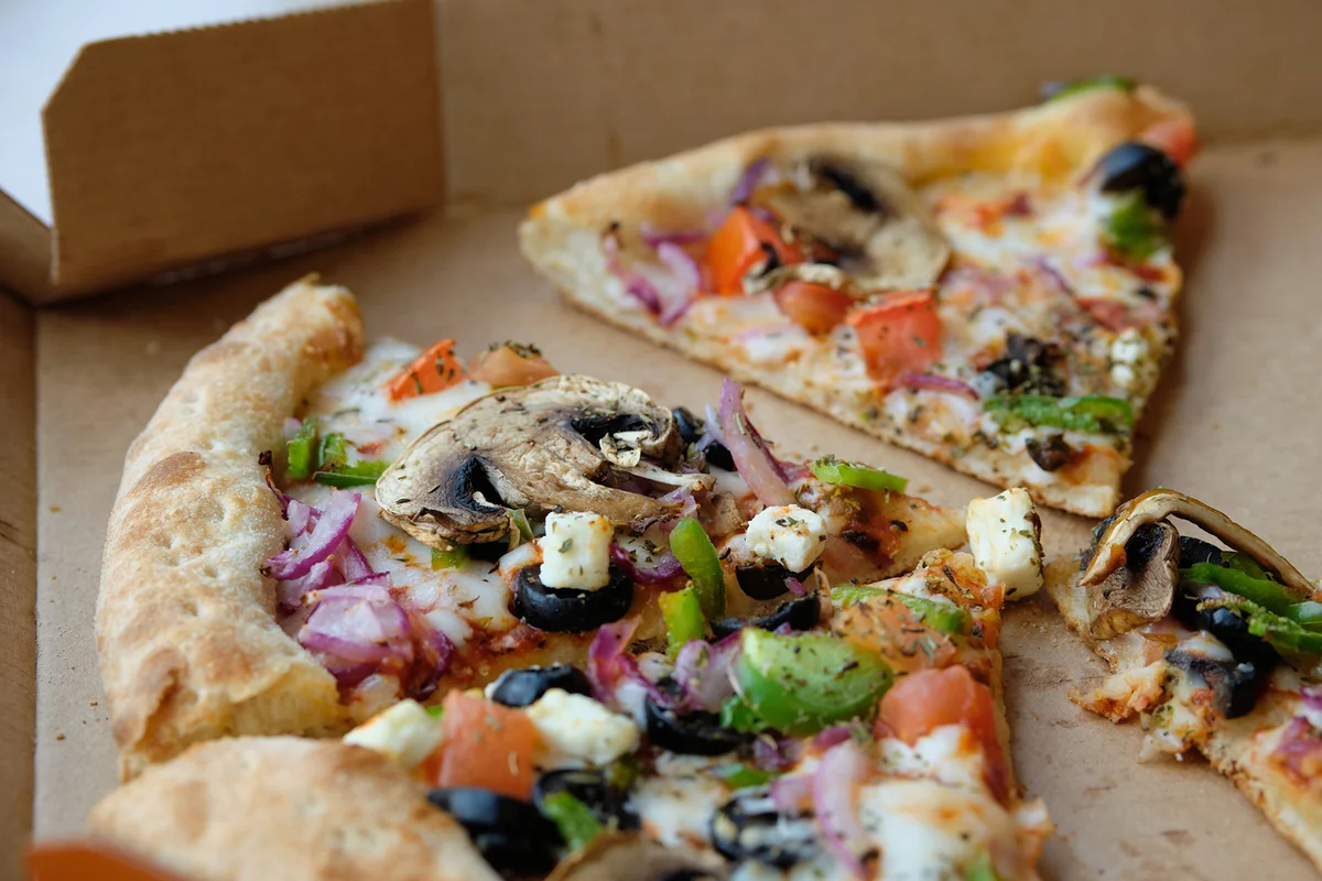 Slices of Italian Vegetable Pizza With cheese and Mushrooms In a Cardboard Box