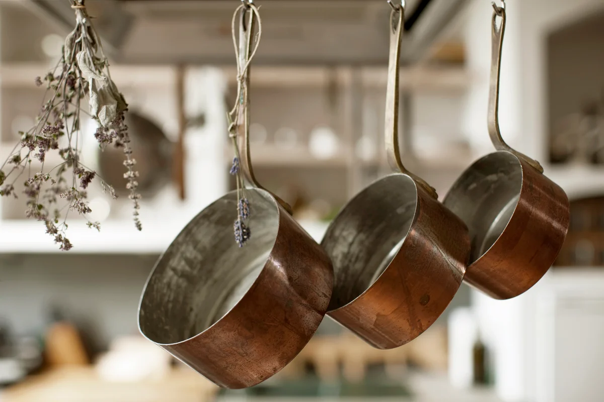 Three saucepans hanging from hooks