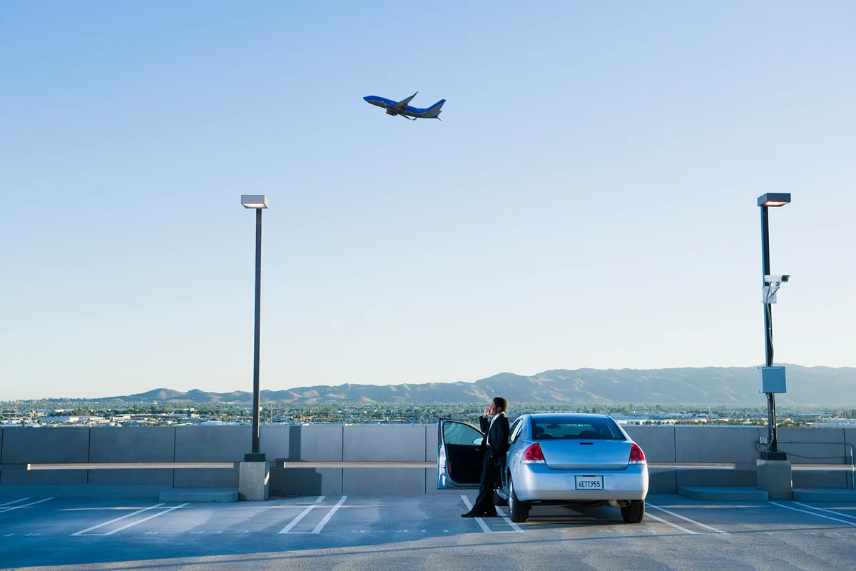 African businessman standing by car at airport