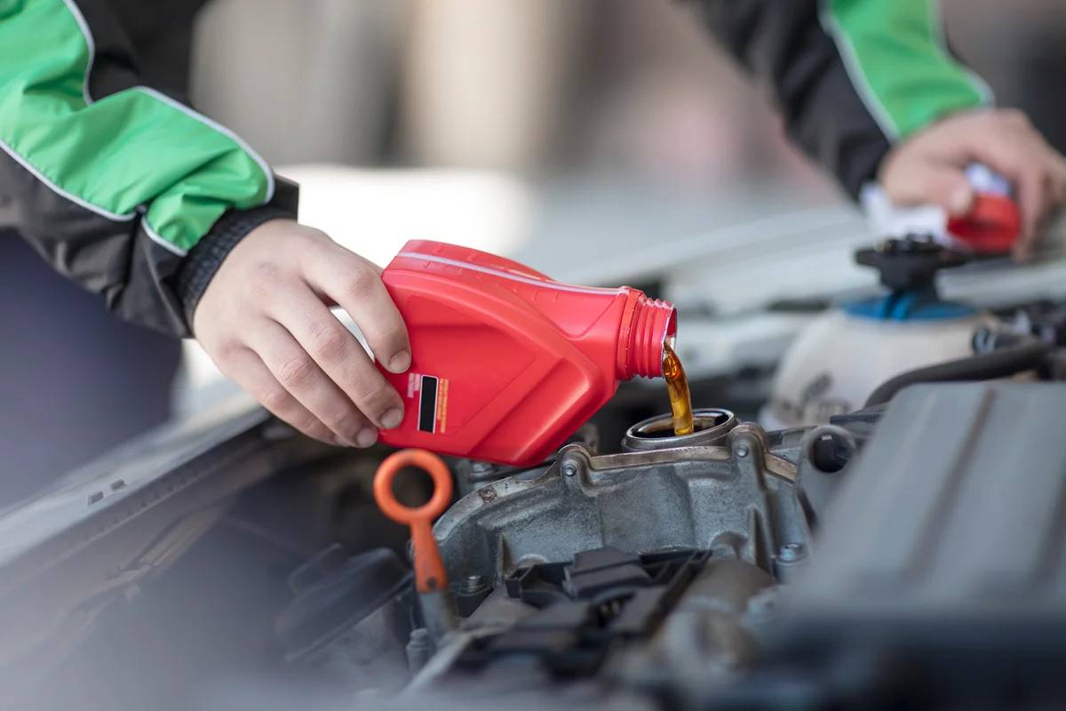 Man filling up car with motor oil
