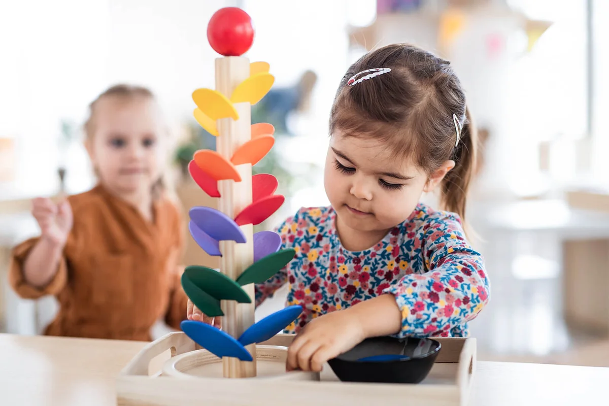 Two pre-school girls playing with marble run indoors in nursery