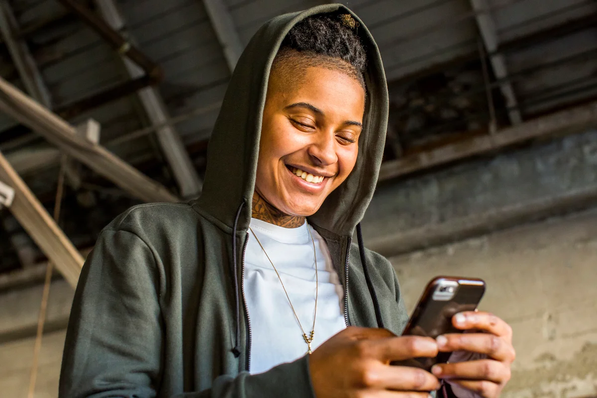 person with masculine style wearing gold necklace texting on their phone