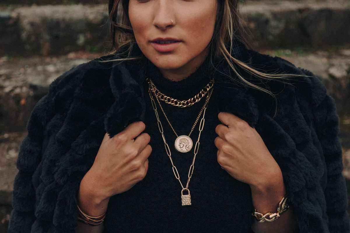 woman wearing black shirt and chunky gold layered necklace with charms