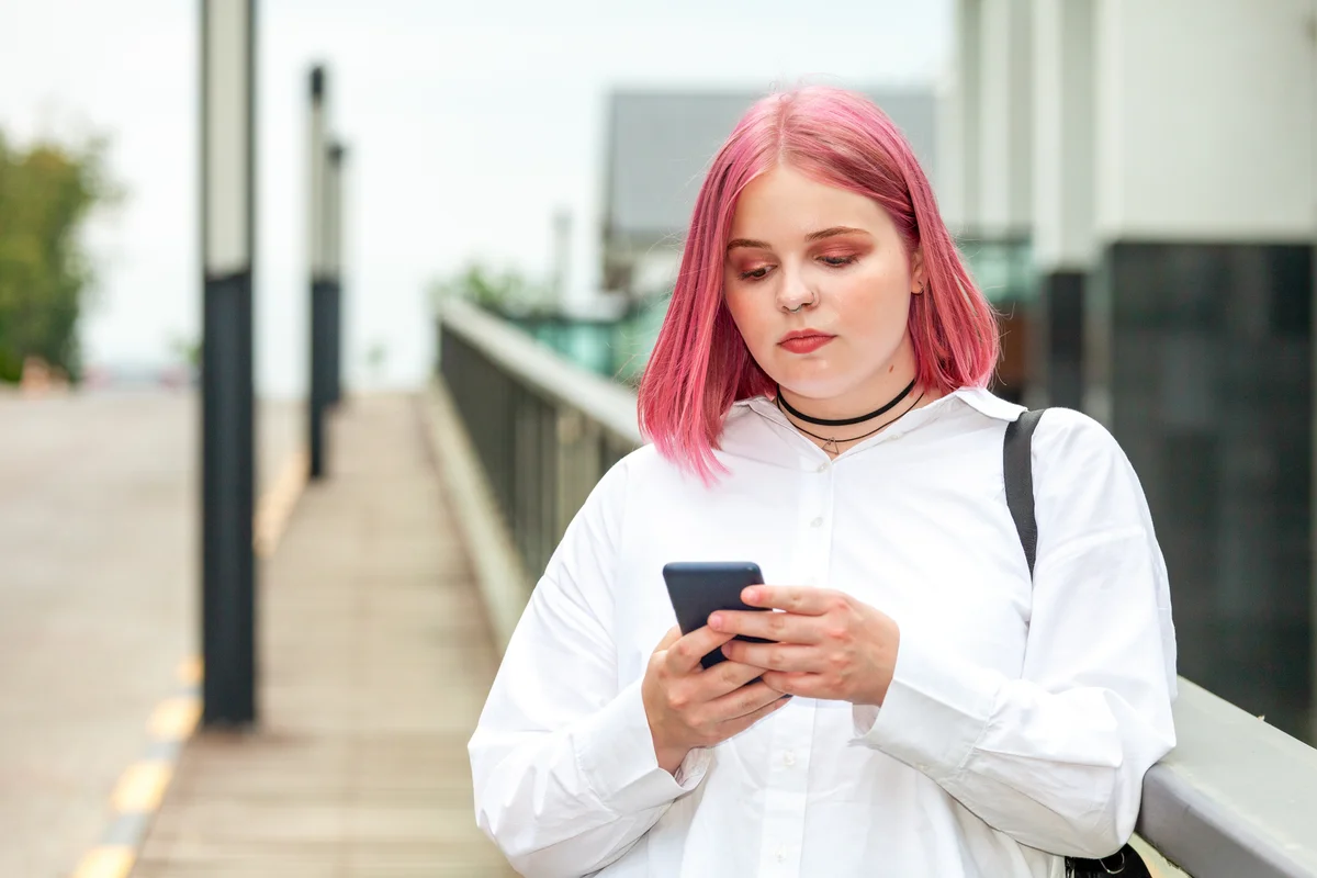 woman on her phone with pink hair and wearing choker necklace